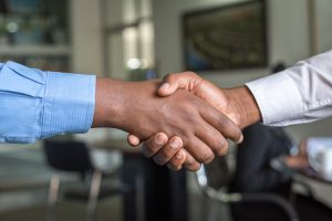 Diverse business leaders shake hands, business deal in office setting contract mediation deal negotiation